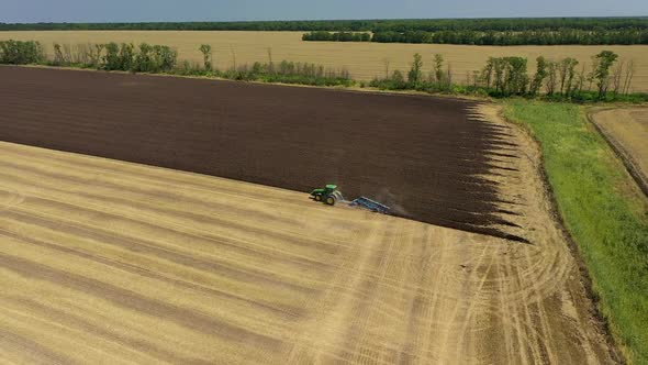 A Tractor Plows a Harvested Corn Field for Future Planting. View From Above alt