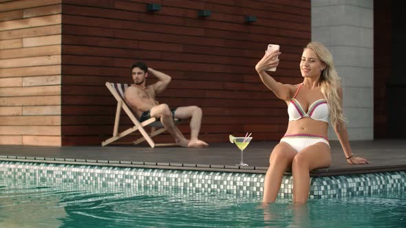 Young Woman Taking Mobile Selfie in Swimming Pool. Sexy Woman Posing for Selfie alt