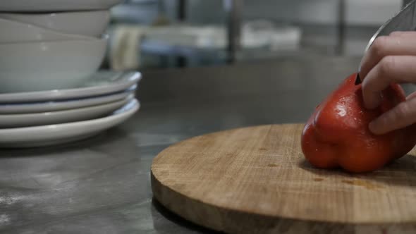 Men's Hands Cut Red Bell Pepper on a Wooden Cutting Board