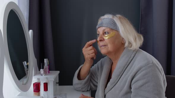 Old Senior Elderly Woman Grandmother Applying Anti-wrinkle Eye Patch, Putting Makeup on at Home alt