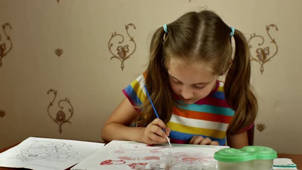 The Young Artist Enthusiastically Paints a Picture with Paints