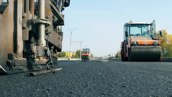 Front View of Bitum Spreaders Riding Along the Road. Constructions Workers Working on Road alt