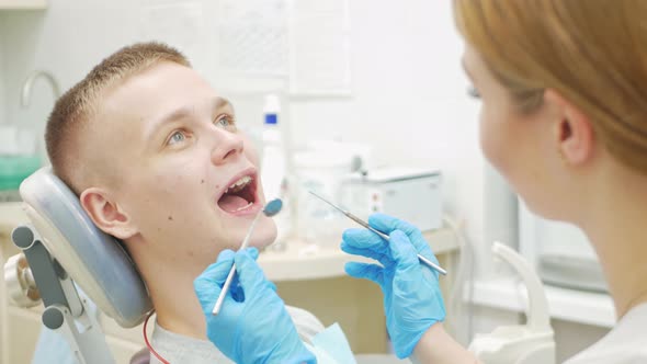European Female Dentist Doctor Treats Patient Examines Mouth and Teeth