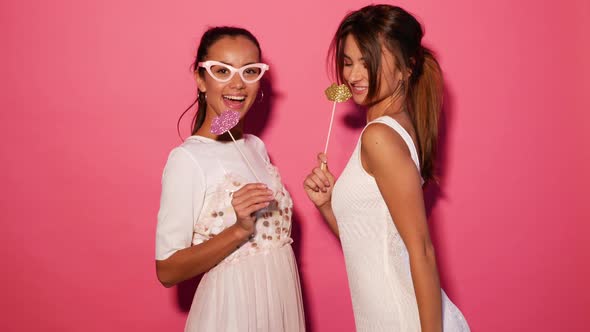 Two beautiful funny women going crazy in paper glasses and big lips on stick