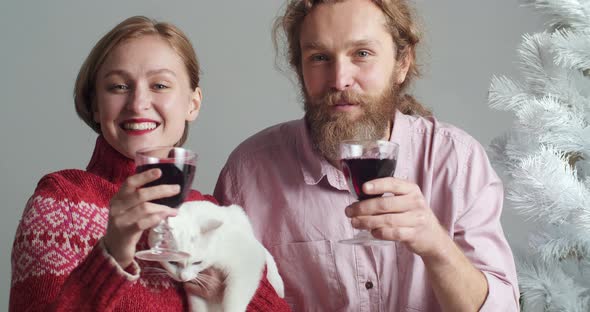 Portrait of Caucasian Family of Young Couple with Pet White Cat Holding Glasses of Wine in Hands alt