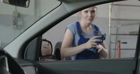 Smiling female mechanic leaning on a car window