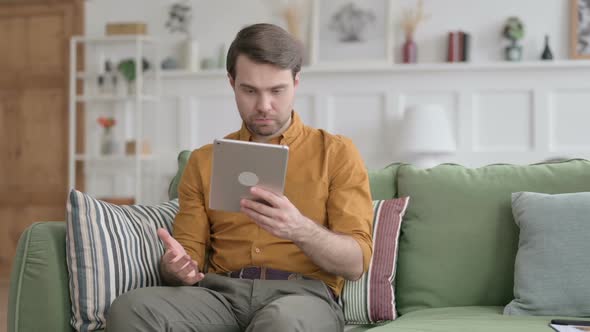 Young Man having Loss on Tablet on Sofa alt