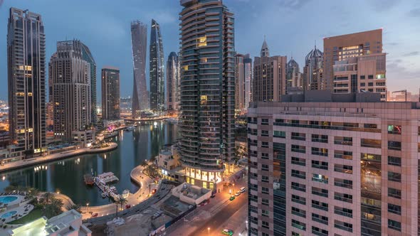 Aerial View of Dubai Marina Residential and Office Skyscrapers with Waterfront Night to Day alt