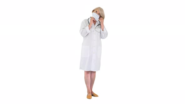 Senior Woman Doctor Putting on Medical Mask Looking at the Camera on White Background