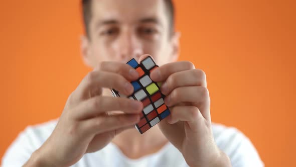 Kiev Ukraine July 30 2020 Rubik's Cube in the Hands of a Man in Studio on Orange Color Background alt