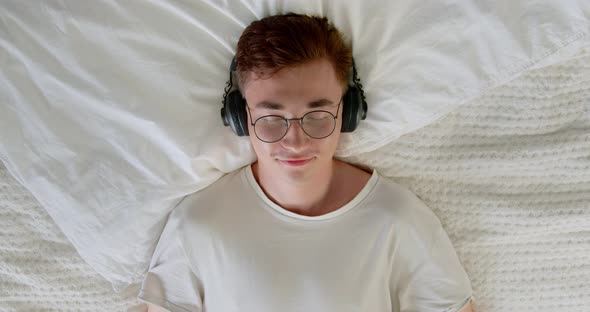 Calm young man enjoys listening chill music audio sound meditating feeling no stress at home.  alt