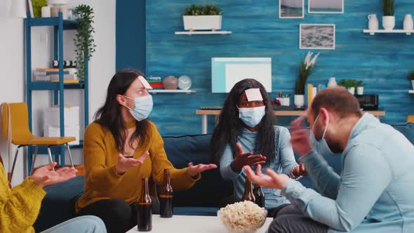 Multiracial Colleagues with Protective Masks Playing Game with Sticky Notes alt