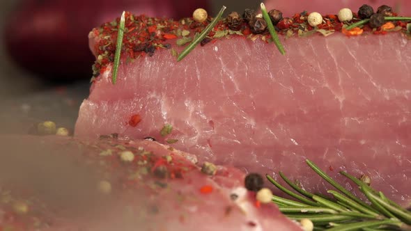Close Up of Knife Cuts Piece of Fresh Pork Sprinkled with Peppercorns Spices Seasonings