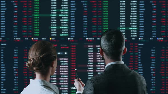 Colleagues Traders are Working with Multiple Computer Screens Full of Charts and Data Analysis and alt