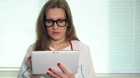 Female Doctor Working with Tablet Computer and Looking at Camera and Smiling