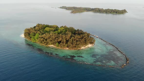 Cinematic aerial view of an island in the middle of the ocean at sunset.