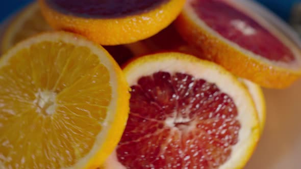 Juicy Ripe Slices of Red and Yellow Oranges in a White Plate Slowly Rotate alt