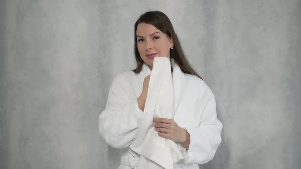 Woman in a Bathrobe Wipes Her Face with a White Terry Towel After Taking Shower