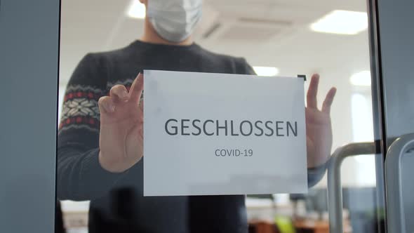 Closeup Man Hanging a Sign Closed on the Glass Door alt