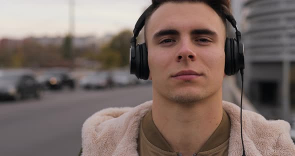 Man Puts on Headphones in City Listening Music alt