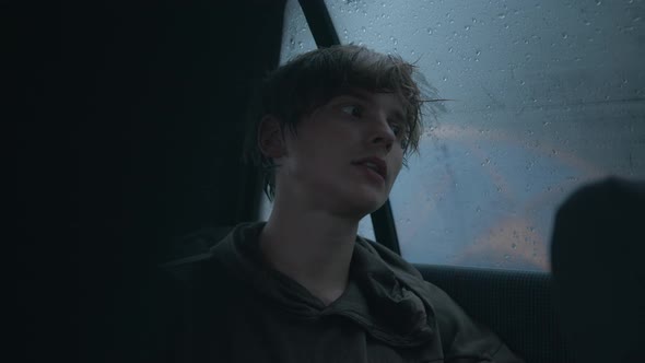 Hipsterlooking Young Man Sits in a Car in the Rain and Gives an Interview Into the Lavalier alt