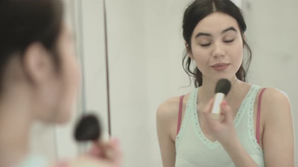 Pretty Young Asian female applying make up in bathroom