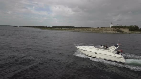 Motorboats On The Water Lighthouse In The Background Drone Follows Boat Wide Shot