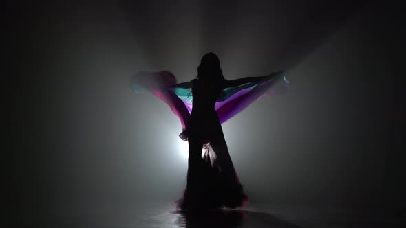 Girl Dancing Belly Dance with Shawl. Sihouette . Black Smoke Background alt
