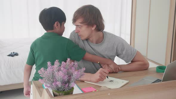 Young father drawing on book computer and son persuade play while busy at home. alt