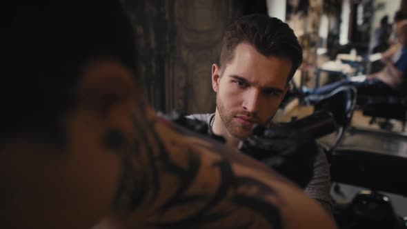 Focus caucasian man tattooing woman at the studio. Shot with RED helium camera in 8K. alt