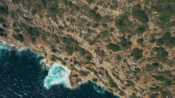 Aerial drone top down view of rocky cliff with evergreen plants
