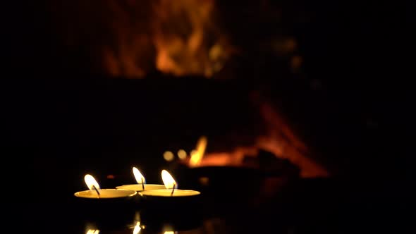  three candles on a black background with a fireplace flame.