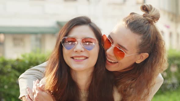 Portrait of Two Young Smiling Hipster Women Friends Wearing Sunglasses of Heart Shape. Lesbian Girls alt