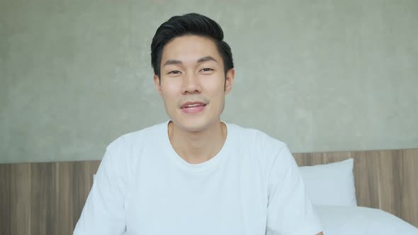 smart casual asian adult mature male in casual cloth sitting on bed in bedroom alt