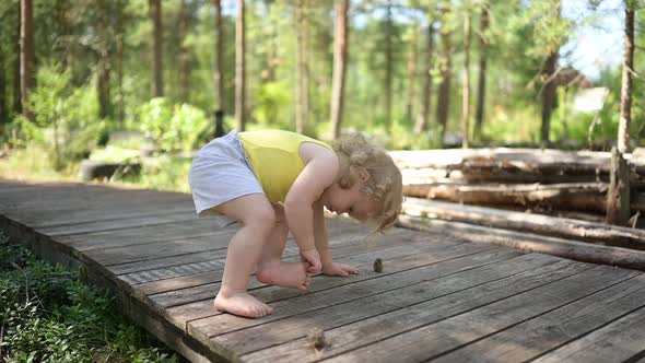 Little Funny Cute Blonde Girl Child Toddler in Yellow Undershirt and Grey Shorts Walking Playing on
