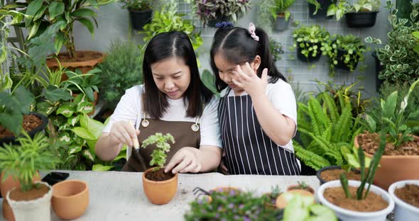 Mother teaching daughter to plant trees alt