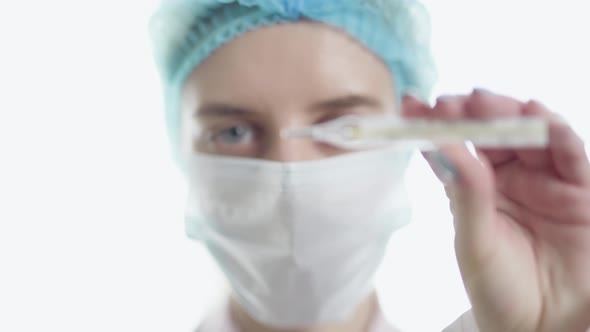 A Female Doctor in Medical Uniform is Looking at Camera and Showing Medical Mercury Thermometer alt
