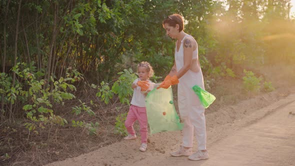 Little Girl Helps Mother Collects Plastic Garbage on Nature to Save Environment From Pollution alt