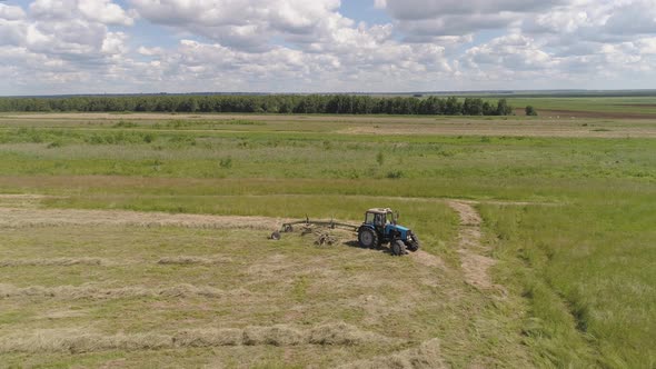 Tractor with Rake Tedders on the Farm Field alt