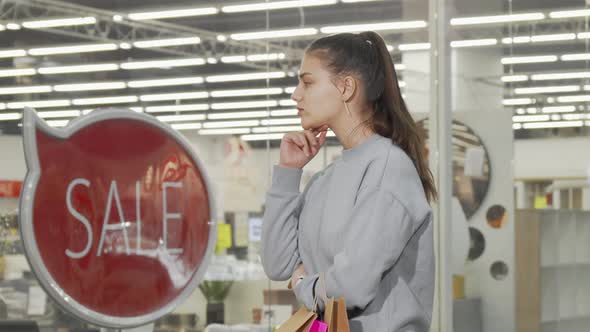 Young Woman Looking at the Display of a Store at the Mall