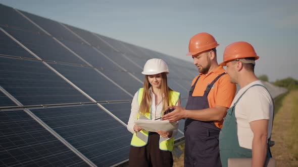 Engineers Use Drawings on the Solar Farm in Special Uniform Standing Look Around alt