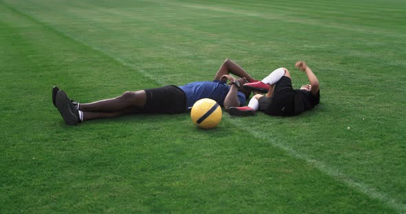 Diverse Father and Son Playing on Football Pitch During Break alt