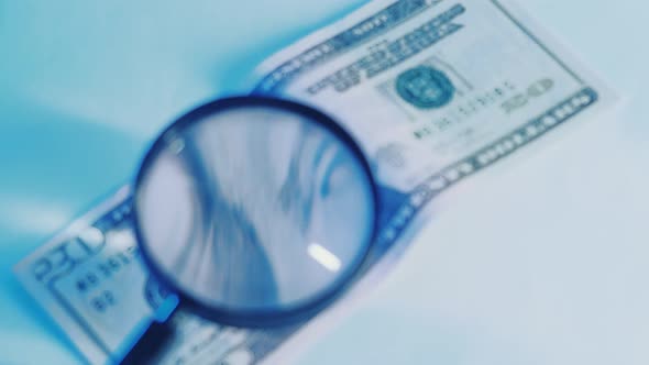 Close Up of Dollars Being Checked By the Police with a Magnifying Glass alt