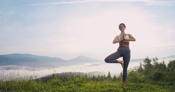 Active Woman Balancing on One Leg and Meditating Outdoors alt