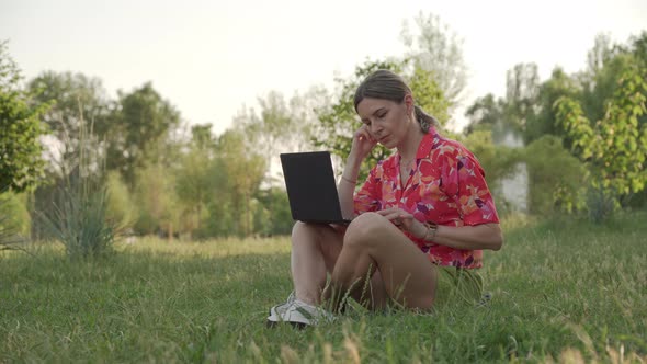 A Female Freelancer is Working on a Project Using Her Laptop in a Public Park