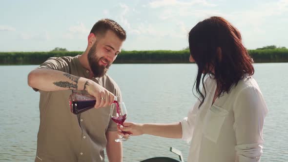 Slow motion shot of man pouring at red wine in glass of woman alt