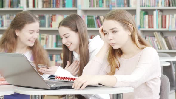 Teenage Girl Looking Tired and Bored While Studying at the Library alt