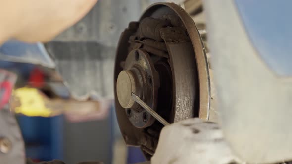 Worker Cannot Remove the Protective Cap From the Vehicle Hub with a Screwdriver alt