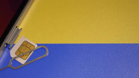 Closeup Shot of the Ukrainian Flag and a Smartphone with a Sim Card alt