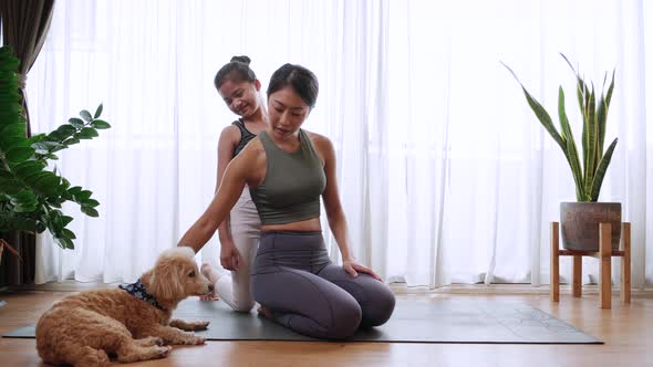 A healthy Little girl enjoys riding the back of her mom during yoga exercise at home